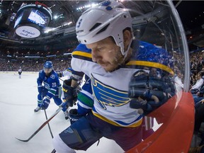 St. Louis Blues' Steve Ott, right, battles Vancouver Canucks' Chris Higgins (20) and Dan Hamhuis, back, for control of the puck during the first period of an NHL hockey game in Vancouver, B.C., on March 1, 2015.