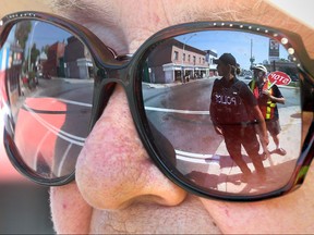 Windsor police Const. Elena Djurovic  and crossing guard  Larry Formagin are reflected in the sunglasses of Theresa McAnally at the corner at Wyandotte and Langlois in Windsor, Ontario on August 6, 2016.   Windsor Police continue their zero tolerance approach.