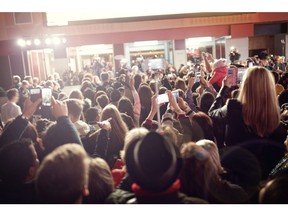 Crowd and fans taking photographs on mobile phones at a red carpet film premiere. Photo by Getty Images.