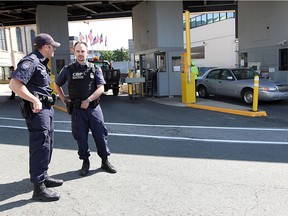 U.S. border officers stand guard at the mouth of the Detroit-Windsor tunnel on Thursday. Officials from Canada and the U.S. held a media conference to give tips on crossing the border during the busy summer travel season.