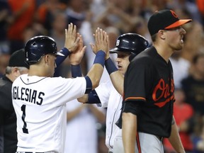 Detroit Tigers' Jose Iglesias (1) and Ian Kinsler celebrate scoring on a J.D. Martinez single as Baltimore Orioles pitcher Kevin Gausman, right, walks to the mound during the fifth inning of a baseball game in Detroit on Sept. 9, 2016.