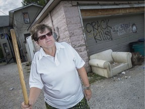 Diane Beck sweeps up the garbage in the alley behind a house she owns on the 400 block of Bruce Avenue. She's upset at the dumping of furniture in the alley.