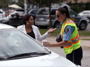 A driver questions a municipal bylaw officer after a ticket was issued in front of Massey Secondary School on Sept. 21, 2016 in Windsor, Ont.