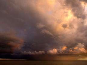 Ominous clouds from a rain storm are lit up by the setting sun on Lake Erie, Saturday, Sept. 10, 2016.