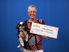 Suzanne Allair of Amherstburg holds up the $50,000 prize cheque she received from the OLG (and also her dog). Allair won the money playing Instant Crossword.