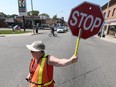 Crossing guard Theresa McAnally assists a pedestrian across Wyandotte Street at Langlois in Windsor on Aug. 6, 2016. Windsor Police continue their zero tolerance approach to those who fail to stop for crossing guards and school buses.