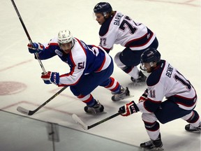 Windsor Spitfires Jalen Chatfield, left, keeps his head up while being checked by Saginaw Spirit Jesse Barwell and Kris Bennett, right, during the first period of OHL action from WFCU on Nov. 27, 2015.