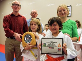 Young Judo students Caroline Hornick, left, and Briar Davies hold a new, life-saving defibrillator and dedication ceremony plaque which were donated in memory of Corporal Andrew Grenon by the Dave Mounsey Memorial Fund at the Terra Nova Judo Club on Dougall Avenue October 18, 2016. Attending the ceremony were Grenon's brother, Matthew Charbonneau, left, and Grenon's parents, Mike and Theresa Charbonneau, right. The defibrillator is the 60th to be donated by the Dave Mounsey Memorial Fund and the second for Windsor, with the first being donated in memory of Windsor Police Const. John Atkinson. Dave Mounsey Memorial Fund founder Const. Patrick Armstrong was on hand to deliver the defibrillator to Judo instructor Byron Hornick and his class. (NICK BRANCACCIO/Windsor Star)