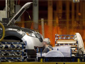 A line worker works on a car at the Ford Motor plant in Oakville on Jan. 4, 2013.