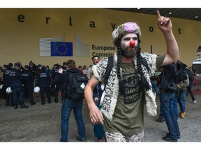 A man dressed like a clown with a sticker and a t-shirt reading "Transatlantic Trade and Investment Partnership (TTIP) game over" gestures as behind him demonstrators face Belgian police officers during a protest against the EU-Canada Comprehensive Economic and Trade Agreement (CETA) at European Union Commission headquarters in Brussels on October 27, 2016. Belgium announced on October 27, 2016 a breakthrough in talks to secure a landmark EU-Canada trade deal by winning over the leaders of a recalcitrant Belgian region, potentially snapping a deadlock which threatened European credibility anew. However, the announcement came too late for EU leaders and Canadian Prime Minister Justin Trudeau to go ahead with a signing ceremony in Brussels on October 27, 2016.  /
