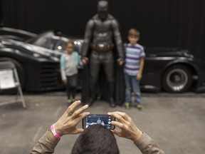 Marco Carnevale takes a photo of his children, Graham Carnevale, 9, and Stella Carnevale, 7, as they pose with Batman at Windsor ComiCon at Caesars Windsor, Saturday, Oct. 15, 2016.