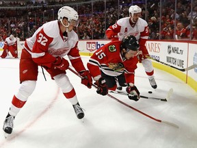 Artem Anisimov (15) of the Chicago Blackhawks gets airborne trying to control the puck between Louis-Marc Aubry (32) and Jonathan Ericsson (52) of the Detroit Red Wings during a preseason game at the United Center on Oct. 4, 2016 in Chicago, Ill.