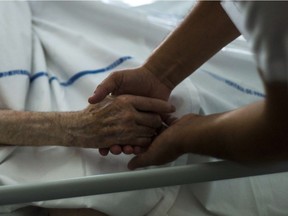 A file picture taken on July 22, 2013 shows a nurse holding the hand of an elderly patient at the palliative care unit of the Argenteuil hospital, outside Paris.