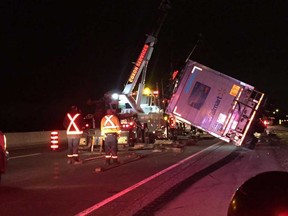 Workers attempt to right a tractor trailer that tipped over on Highway 401 in the Tecumseh area during the early morning hours of Oct. 24, 2016. The trucker, Gurwinder Chhina of Hamilton, has been charged with careless driving.