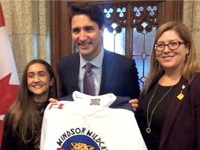 Jada Malott, a Grade 7 student at John Vianney school in Windsor, left, presents Canadian Prime Minister Justin Trudeau with a Windsor Wildcat hockey jersey during her visit to Ottawa on Oct. 5, 2016. Essex MP Tracey Ramsey is on the right.