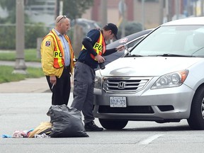 LaSalle police officers investigate the scene after a pedestrian was struck by a van on Front Road at Laurier Drive in LaSalle, Ont., on Oct. 3, 2016.