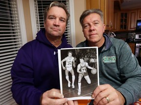 Hunt Hool, left, and Andy Kiss remember one of the greatest high school basketball championship games of all time when Kiss's W.F. Herman teammate John Lukis launched a 60-foot buzzer beater against Hool's Assumption Raiders in 1980. Hool and Kiss hold a photo from that game taken by Windsor Star photographer Bev MacKenzie.