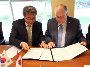 Soo Dong Han, deputy mayor for the city of Guro, South Korea, left, and WindsorEssex Economic Development Corporation chief executive officer Stephen MacKenzie sign a memorandum of understanding to promote business and trade between the two regions.