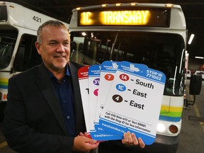 Pat Delmore, executive director at Transit Windsor, holds the new bus stop sign that displays the "text or call" numbers that allow riders to check the ETA of a bus.