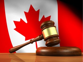 A judge's gavel on a wooden desk is shown with the Canadian flag in the background.