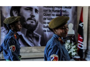 Militia women pass in front of a poster of late Cuban revolutionary leader Fidel Castro, in Havana, on November  29, 2016. Cuban revolutionary icon Fidel Castro died late November 25 in Havana. His ashes will be buried in the historic southeastern city of Santiago on December 4 after a four-day procession through the country. /