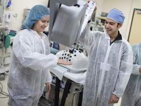 Madison Oliphant, 16, left, from Massey Secondary School, and Elias Elanah, 16, from L'Essor Secondary School, are given hands-on instructions on the da Vinci Si surgical robot at Windosr Regional Hospital - Met Campus, Saturday, Nov. 26, 2016.