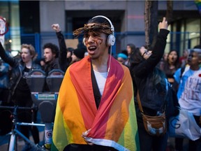 A young man draped in a rainbow flag shouts as he and other protesters hold a rally against U.S. President-elect Donald Trump outside the still under construction Trump Hotel, in Vancouver, B.C., on Thursday November 10, 2016.