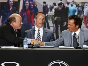 Detroit Mayor Mike Duggan, left, shakes hands with Detroit Pistons owner Tom Gores, right, as Chris Ilitch, Ilitch Holdings, president and CEO, centre, looks on at a news conference in Detroit on Nov. 22, 2016. The Pistons announced they will move downtown Detroit and begin playing at the new Little Caesars Arena, home of the Detroit Red Wings, starting next season.