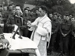 Rev. Major Mike Dalton, Windsor, Ont., serving with an infantry regiment in England, offers mass during a Sunday service "in the field" in Britain. Dalton uses the hood of an army jeep as an altar.