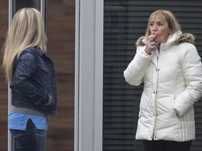 A woman smokes outside city hall on Nov. 24, 2016 where public smoking is still allowed as long as smokers stay at least nine metres away from entrances.