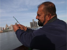 WINDSOR, ON. NOVEMBER 22, 2016. -- Ginan Sto enjoys a cigarette while fishing along the riverfront in Windsor on Tuesday, November 22, 2016.                (TYLER BROWNBRIDGE / WINDSOR STAR)