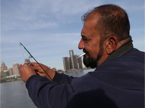 Ginan Sto enjoys a cigarette while fishing along the riverfront in Windsor on Nov. 22, 2016.