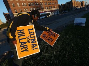 A Detroit resident clears election signs along Woodward Avenue in Detroit following the election on Wednesday, November 9, 2016.