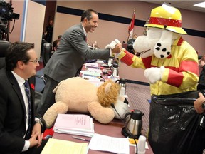 City councillor Bill Marra is greeted by Sparky during the annual donation night at City Council on Nov. 7, 2016. Councillor Irek Kusmierczyk, left, all other councillors and Mayor Dilkens donated gifts to Sparky's Toy Drive.