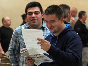 Integram Windsor Seating workers George Rivas, left, and Wojciech Raczka glance at Unifor Local 444 bargaining report highlights during ratification meeting at Fogolar Furlan Club on Nov. 7, 2016.