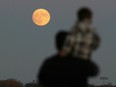Allen Ali and his son, Alexander, watch from Blue Heron Hill as the supermoon rises over East Riverside and Tecumseh Sunday November 13, 2016.