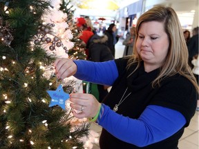 Laura Spencer places an ornament on a tree in memory of her late son, Maiysn, during the start of the Light The Way campaign at Devonshire Mall on Nov. 23, 2016.    Support the CMHA-WECB Bereavement Program and Client Assistance Fund  is raising funds to light the way for those who are struggling this holiday season.