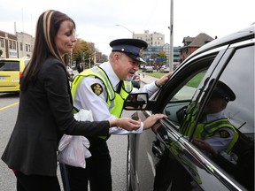 Jennifer Musson, left, and Ontario Provincial Police Staff Sgt. Ed Marocko talk with a motorist while launching the 2016 MADD Red Ribbon Campaign in Windsor-Essex. Musson's sister, Jessica Ondejko, was killed by a drunk driver in 2008. The 2016 MADD Red Ribbon Campaign was launched today along with area police forces at Anderson Funeral home in downtown Windsor.