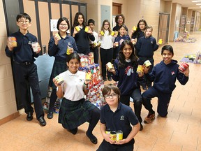 Students from Academie Ste Cecile International School in Windsor, display some of the 10,000 cans collected by 150 students during the annual can drive to benefit the St Vincent de Paul organization.