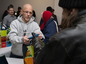 Robert Blair, left, hands out bags of turkey dinner fixings at the Mikhail Holdings turkey giveaway in downtown Windsor, Friday, Dec. 23, 2016.