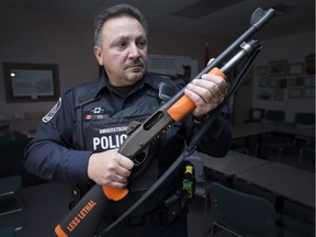 Const. Rocco Pelaccia holds a 12-gauge shotgun fitted to fire a Super Sock, a less lethal option for subduing suspects, at the Amherstburg police station on Dec. 9, 2016.