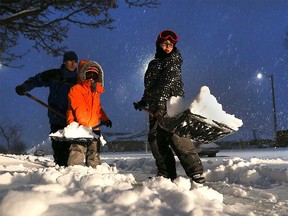 Tate Murtagh (right) lifts a shovel full of snow while his brother Cohen and his father Brian look on in Windsor's east end on Dec. 11, 2016.