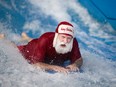 Santa rides the Flow Rider at Adventure Bay Family Water Park for the 3rd annual Swim with Santa, Saturday, Dec. 3, 2016.
