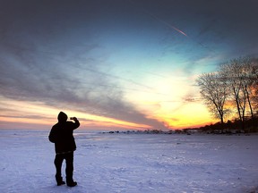 Sam Morrone snaps a photo of the setting sun on the waterfront in Kingsville, ON. on Tuesday, Dec. 20, 2016 on a chilly winter evening.