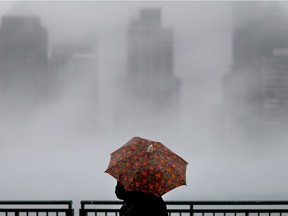 Annarita Fiorino uses the cover of her umbrella to take photos of the foggy Detroit River on a balmy and rainy Boxing Day holiday, Monday, Dec. 26, 2016.