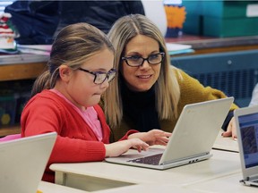 Kim Sidi, right, helps student Mateja Simic as her Grade 3 class works on a programming lesson at St. Rose Catholic Elementary School in Windsor on Dec. 21, 2016.