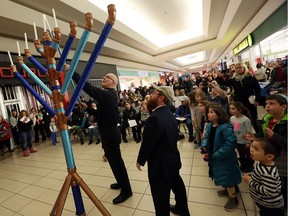 Rabbi Sholom Galperin enlists the help of police Chief Al Frederick to light the menorah during the annual Chanukah celebration at Devonshire Mall in Windsor on Dec. 28, 2016.
