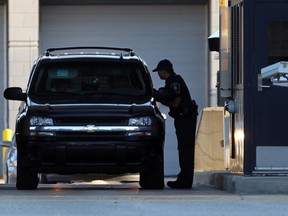 A CBSA officer checks vehicles and occupants at Windsor-Detroit Tunnel international border crossing on Oct. 2, 2012.