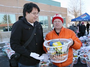 Food basket recipient Bon Halkett, left, is assisted by Re/Max Preferred volunteer Andre Goulet, during Sunday's event on Tecumseh Road East where a team of volunteers assembled Christmas feasts for 1,000 families Dec. 18, 2016.