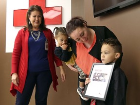 Xzavier McEldowney holds his Canadian Red Cross Rescue Award after a presentation from  Red Cross instructor Lilly LeBlanc on Dec. 5, 2016 in Windsor, Ont. Xavier's mother Alycia and little sister Ariyah look on.